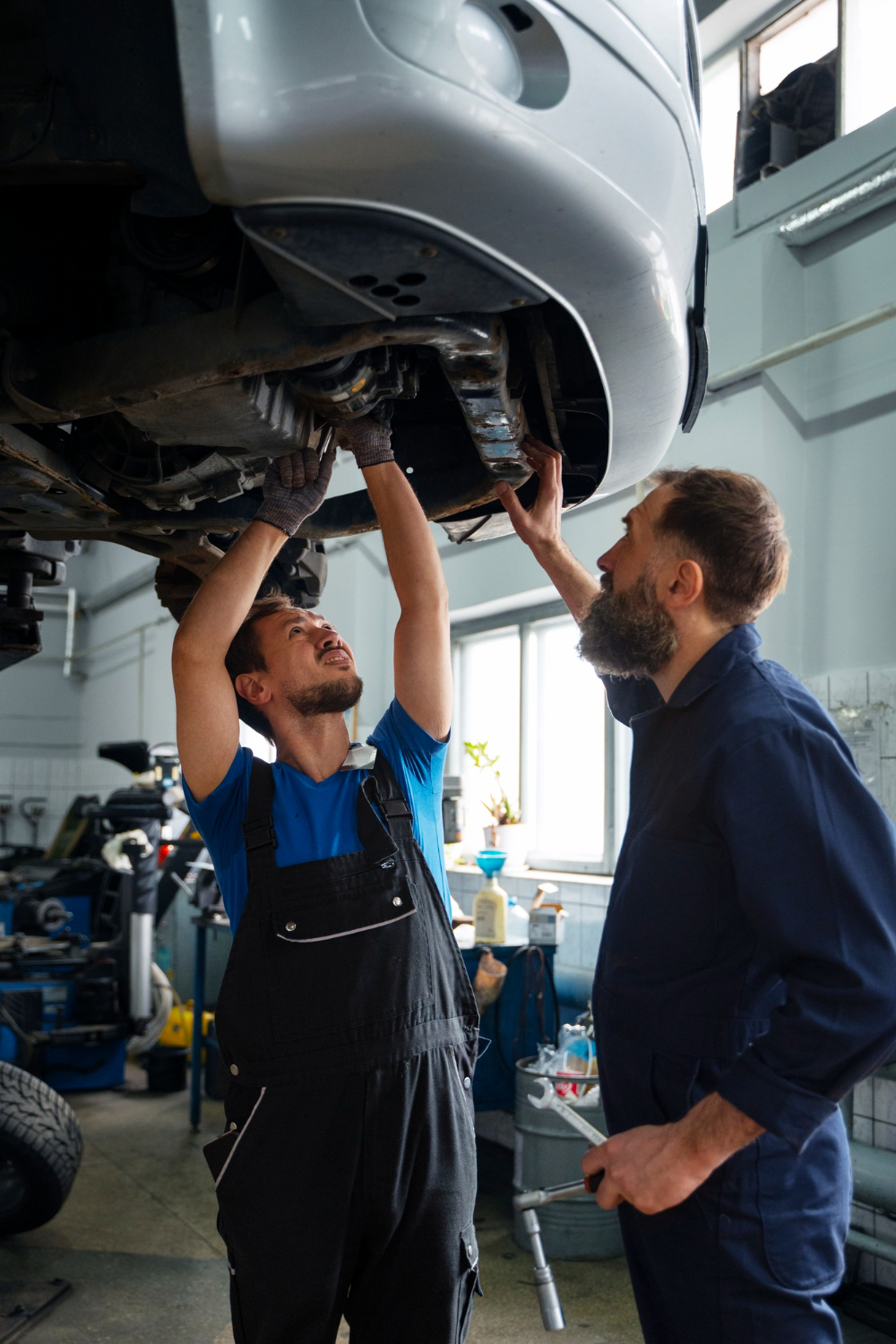 male-mechanics-working-together-car-shop